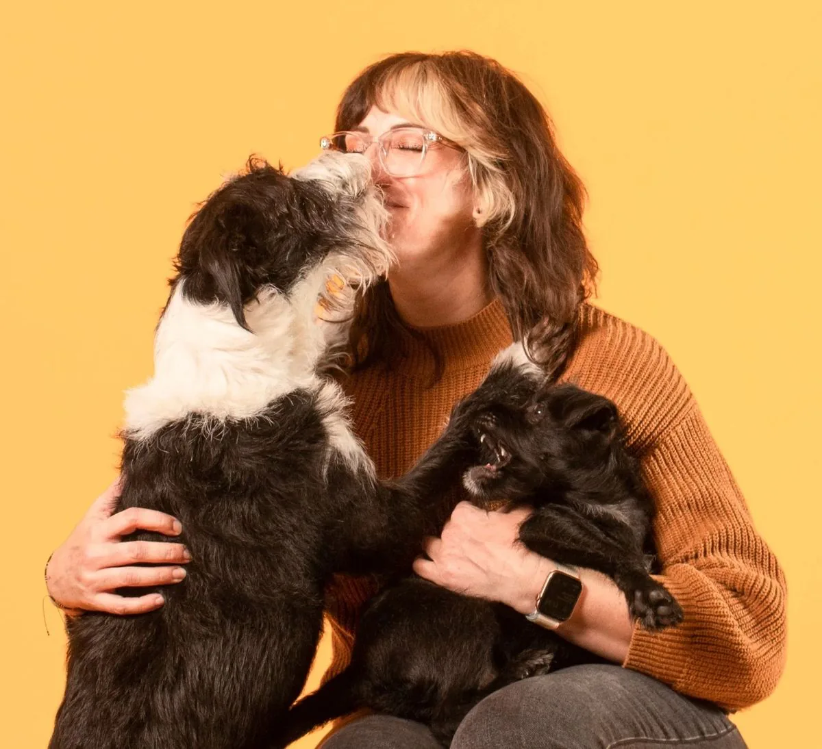 Tutora abraçada com seus dois cães pretos